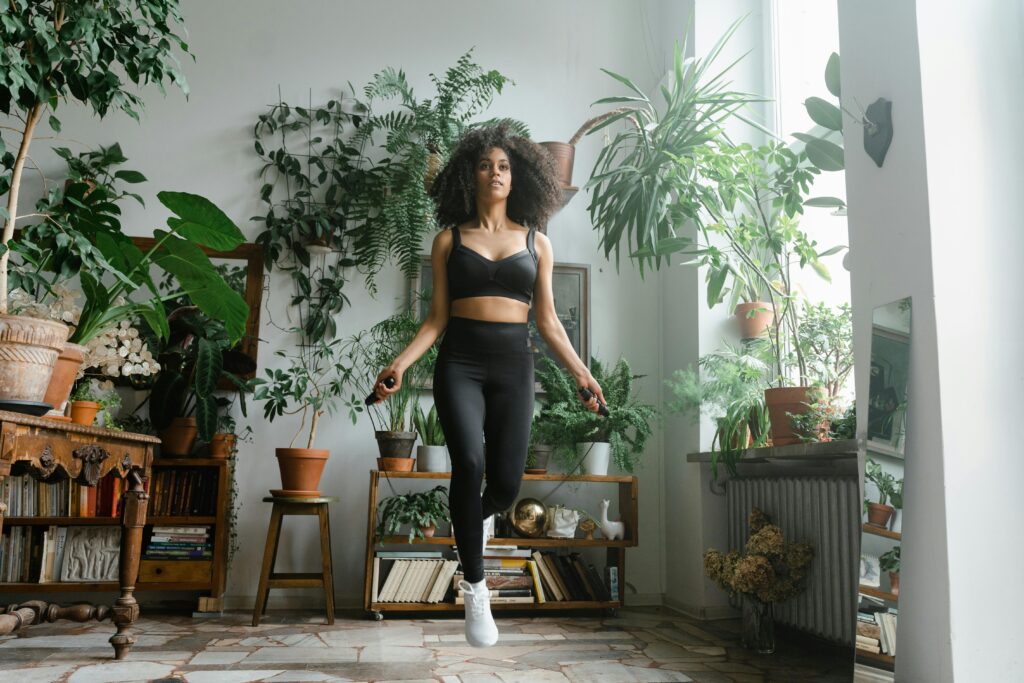 Benefits of jump rope African American woman jumping rope in a plant-filled room, promoting a healthy lifestyle.